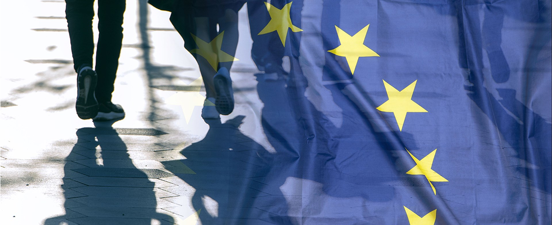 Eine transparente Europaflagge mit vorbeigehenden Menschen und deren Schatten.